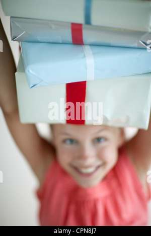 Girl holding pile de cadeaux sur la tête Banque D'Images