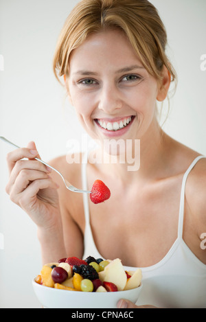 Young woman eating fruit salad, portrait Banque D'Images