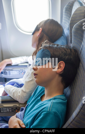 Les enfants dormant sur avion, portant des masques de sommeil Banque D'Images