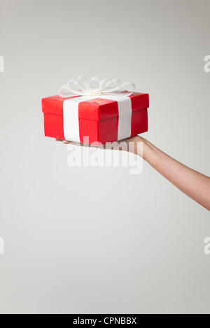 Woman's arm holding out boîte cadeau, cropped Banque D'Images