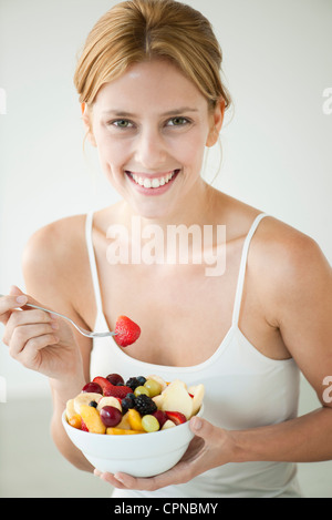 Young woman eating bol de fruits, portrait Banque D'Images