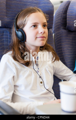 Girl watching film avec des écouteurs on airplane Banque D'Images