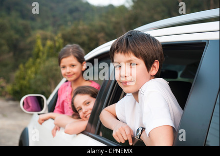 Frères et sœurs se penchant hors de la fenêtre de voiture, smiling, portrait Banque D'Images