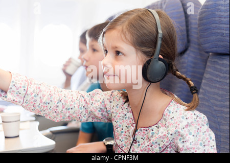 Girl watching film avec des écouteurs on airplane Banque D'Images