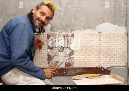 Carreleur travaillant sur une mosaïque dans une salle de bains Banque D'Images