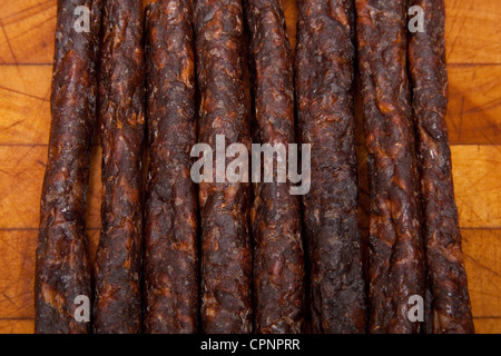 South African épicé Peri peri drywors (saucisson séché) sur un billot de bois. Banque D'Images