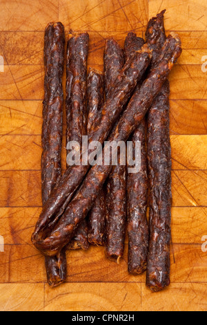 South African épicé Peri peri drywors (saucisson séché) sur un billot de bois. Banque D'Images