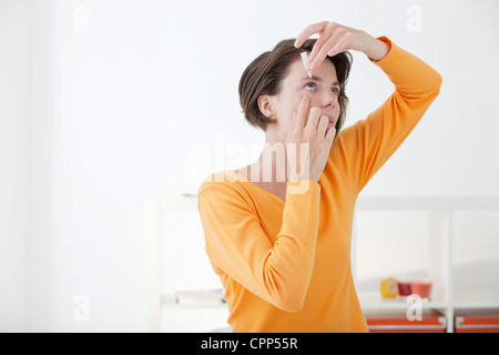 Femme à l'aide de Lotion oculaire Banque D'Images