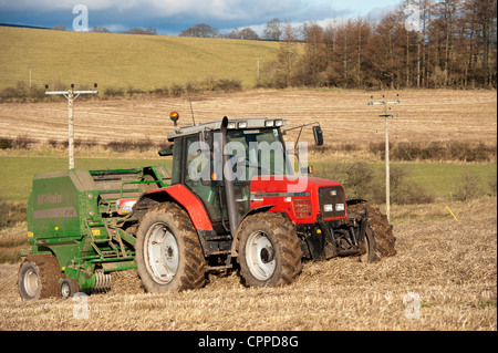 La mise en balles de paille avec McHale et balles rondes tracteur Massey Ferguson. Banque D'Images