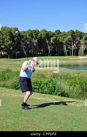 Male golfer hitting sur le lac sur le 8e Trou au Golf Le parcours de Golf Son Parc, Son Parc, Minorque, Iles Baléares, Espagne Banque D'Images