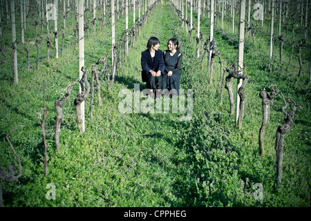 Un couple de vagabond assis au milieu d'un champ de vignes et are smiling Banque D'Images