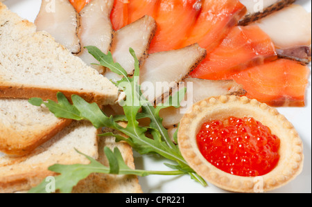 Tranches de poisson fumé sur une plaque et caviar rouge Banque D'Images