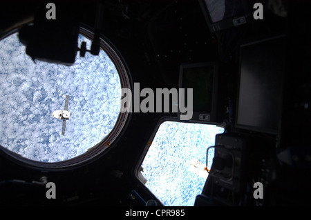 Comme vu à travers les fenêtres de l'ISS le SpaceX Dragon du fret commercial de plaisance s'approche de la Station spatiale internationale le 25 mai 2012 pour le grappin et l'accostage. Dragon est devenu le premier véhicule spatial mis au point d'être lancé à l'ISS. Banque D'Images