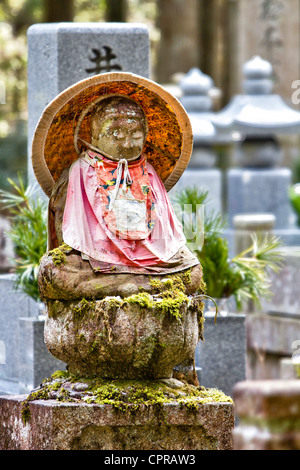 Une statue bouddhiste de Jizo-bosatsu, feuille de lotus en pierre japonaise, portant un bavoir rouge et un chapeau de paille conique dans le célèbre ancien cimetière d'Okunoin à Koya au Japon. Banque D'Images