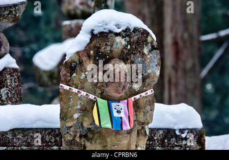 Le Japon, Koyasan, Okunoin cemetery. La neige ancienne woren Jizo de pierre-bosatsu statue bouddhiste sur pierre. bibbed. L'hiver Banque D'Images