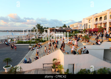 Les gens à regarder le coucher du soleil sur les marches du centre commercial donnant sur la plage de Kuta. Banque D'Images