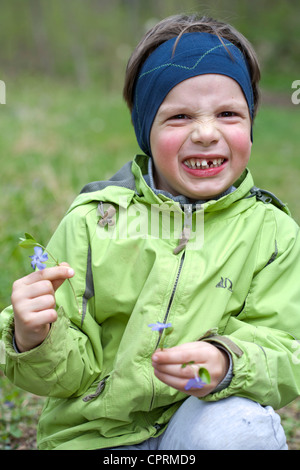 Garçon avec gap cueillette des fleurs au début du printemps. Banque D'Images