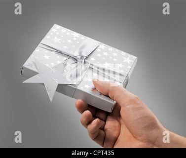 Homme tenant une boîte cadeau (contient un CD) dans sa main. Banque D'Images