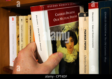 Une main prendre Charles Dickens notre ami commun à partir d'une bibliothèque Banque D'Images