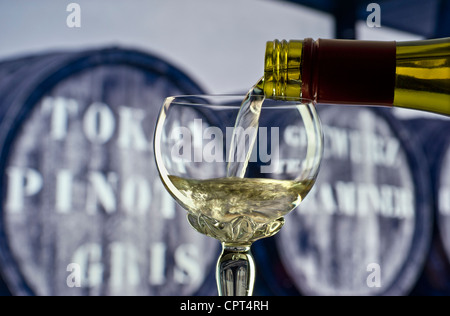 Verser le verre de vin d'Alsace blanc traditionnel à longue tige de verre déco orné avec des tonneaux de vin derrière Banque D'Images