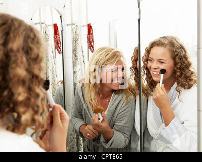 Young woman applying make-up avec la fille dans le miroir Banque D'Images