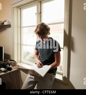 Teenage boy using laptop in room Banque D'Images