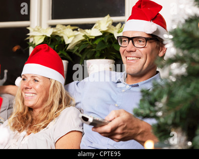 Couple Santa hats sur canapé Banque D'Images