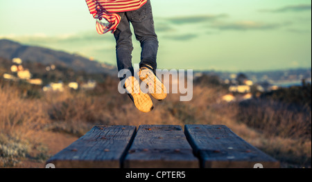 Garçon sautant sur une table de pique-nique Banque D'Images