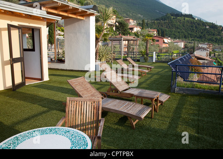 Des chaises longues en bois sur le gazon artificiel de terrasse donnant sur le lac de Garde Italie Banque D'Images