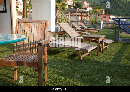 Des chaises longues en bois sur le gazon artificiel de terrasse donnant sur le lac de Garde Italie Banque D'Images