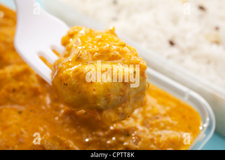 Pièce montée des fourches des Affaires indiennes à emporter repas de poulet curry bhuna ou bhoona avec riz pilaf indien sur fond bleu. Banque D'Images