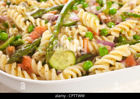 Salade de pâtes alimentaires faites avec les asperges, les pois, l'oignon rouge, de concombre et de morceaux de saumon fumé sur la gauche. Banque D'Images