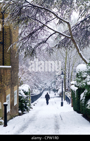 La figure solitaire de promenades à travers la neige profonde dans la région de Holly Place dans le quartier verdoyant de Hampstead, au nord de Londres, Royaume-Uni Banque D'Images