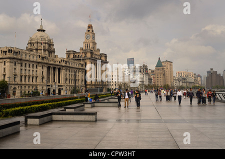 Des groupes de touristes en balade sur une promenade bund humide après un orage avec de vieux bâtiments de Shanghai Chine Banque D'Images