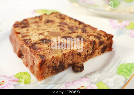 Un gâteau de fruit avec des noix qui ne contient pas de matières grasses, connu sous le nom de thé irlandais du pain. Sur pretty pink vaisselle pour le thé l'après-midi. Banque D'Images