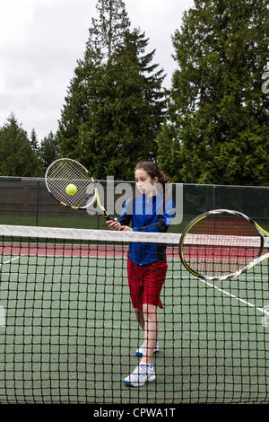 Jeune fille en tenant à l'adversaire contre volley avec net vert des arbres en arrière-plan