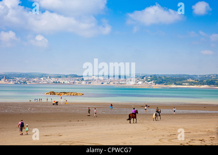 Les cavaliers sur la plage de Mount's Bay à Cornwall Marazion England UK avec la ville de Penzance au-delà Banque D'Images