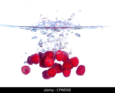 Les framboises rouges tombe sous l'eau avec une éclaboussure, isolé Banque D'Images