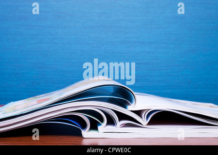 Magazines sur table avec mur bleu derrière. Copie espace peu profond, DOF. Banque D'Images