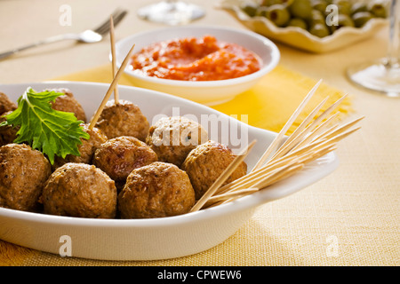 Des tapas espagnoles, albondigas ou boulettes de viande avec sauce tomate, olives en arrière-plan. Banque D'Images