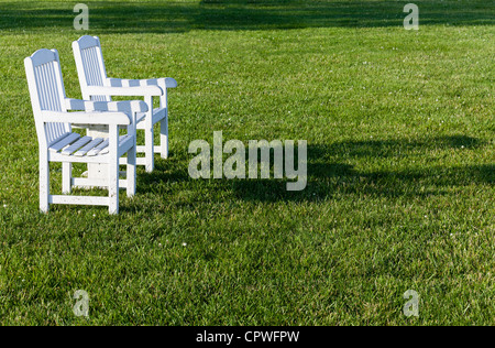 Assis sur des chaises de patio vide pelouse en fin d'après-midi soleil Banque D'Images