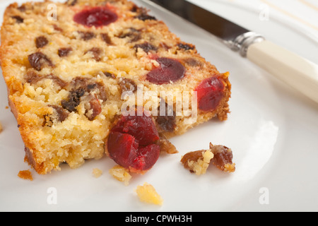 Une tranche de gâteau aux fruits de noix de coco humide délicieusement, farcie de goodies comme noix de coco, cerise, citron et raisins secs. Banque D'Images