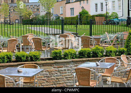 En osier et de tables en verre moderne à un restaurant en plein air en Angleterre Banque D'Images