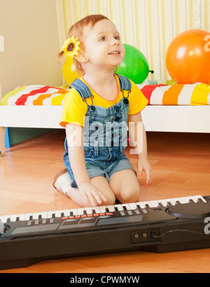 Petite fille jouant du piano assis sur le plancher Banque D'Images