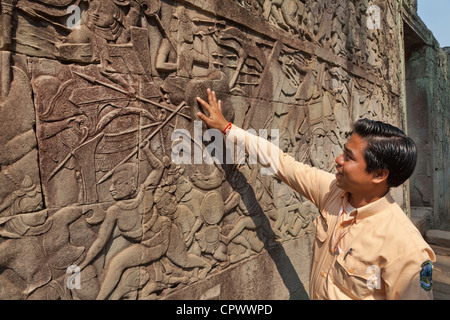 Tour guide expliquant l'histoire des panneaux en pierre sculptée, Ta Prohm, Angkor, la Province de Siem Reap, au Cambodge. Banque D'Images