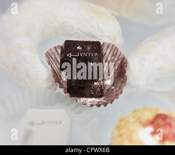 Un clavier d'ordinateur entrez bouton créé à partir de gâteau au chocolat au milieu des pâtisseries différentes Banque D'Images