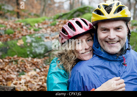 Portrait of mature couple portant des casques de vélo en forêt Banque D'Images