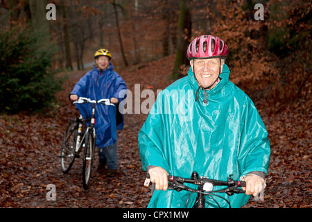 Senior couple cycling in forest Banque D'Images