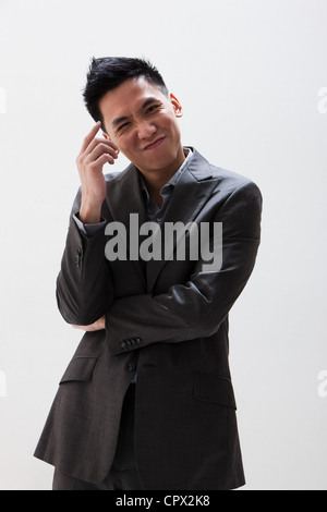 Young Asian businessman scratching head, studio shot Banque D'Images