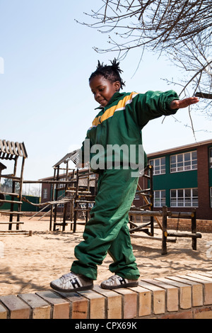 Une jeune fille en équilibre sur un mur à l'extérieur, l'école primaire, Meyerton Meyerton, Gauteng Banque D'Images